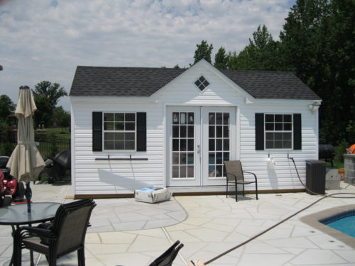 white a frame dormer shed next to pool