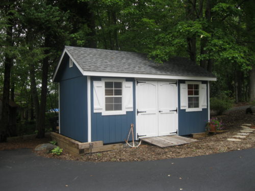 blue classic cottage shed sitting beneath trees
