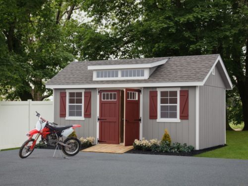 classic studio dormer shed with maroon doors and dirtbike