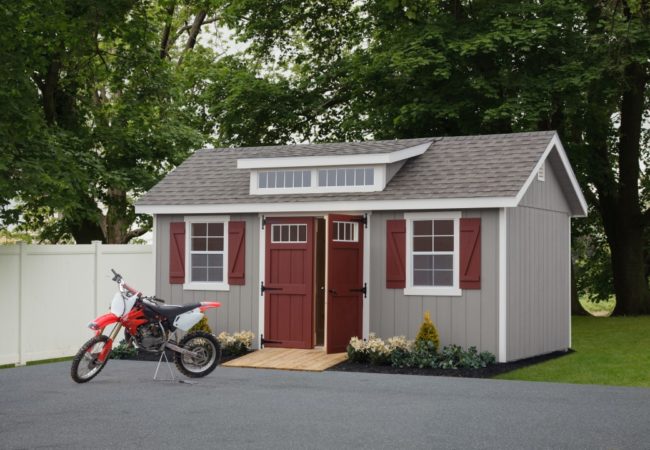 classic studio dormer shed with maroon doors and dirtbike