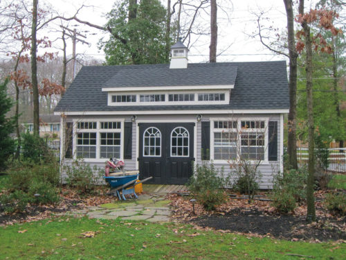 custom classic cottage shed with garden equipment in front