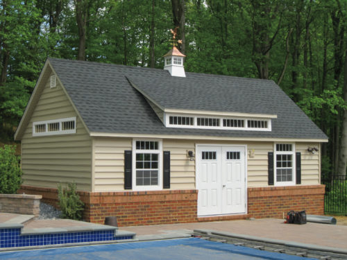 custom classic cottage shed sitting next to swimming pool