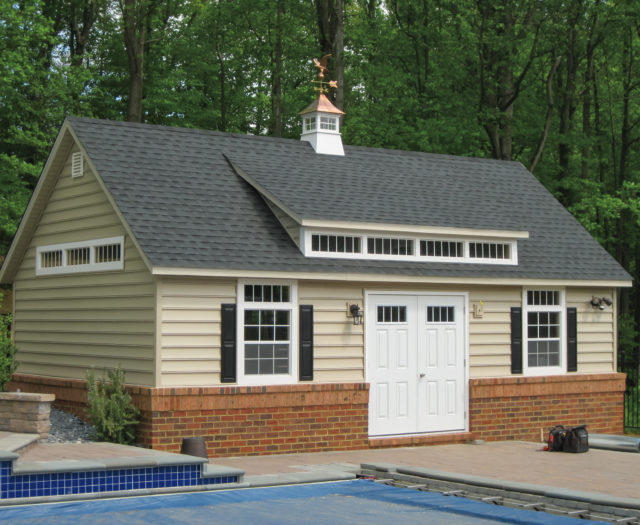 custom classic cottage shed sitting next to swimming pool