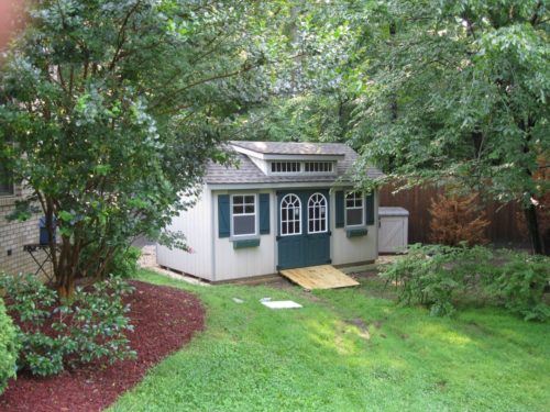 classic studio dormer shed in backyard surrounded by trees