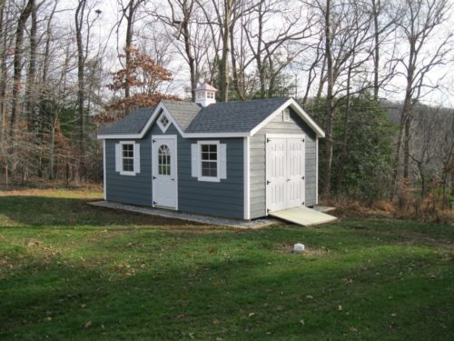blue classic a frame dormer shed in front of trees