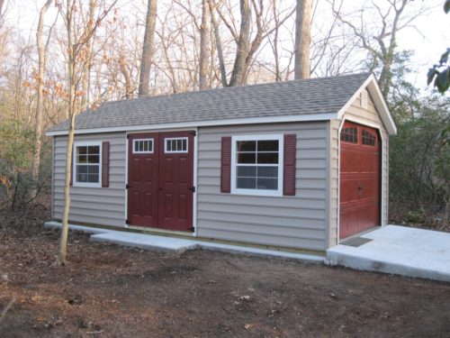 amish built classic cottage garage with red doors and concrete ramp