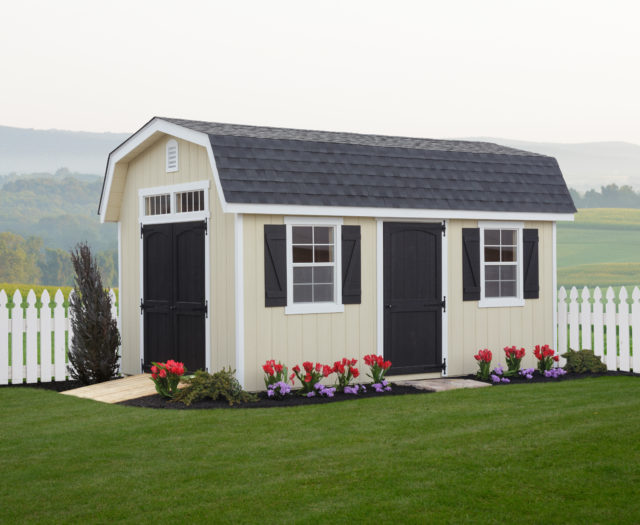 classic dutch barn shed in front of white picket fence