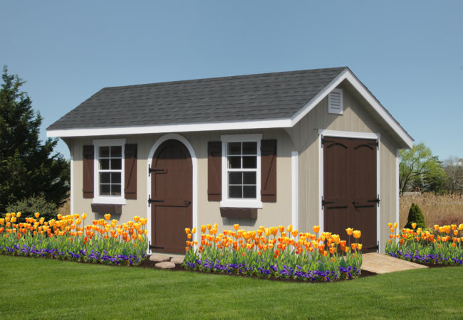 classic quaker shed with brown doors and flowers in front