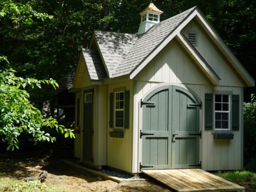 alpine shed with green doors sitting in shade