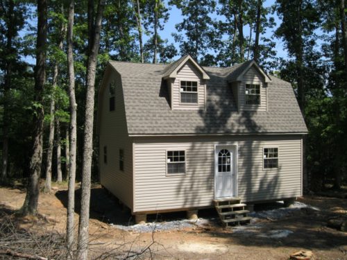 amish built two story dutch barn sitting in woods with white door