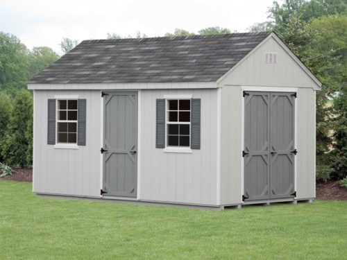 grey cape shed sitting on grass in front of trees
