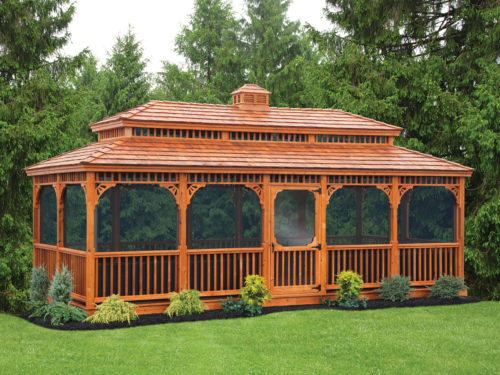 large wooden gazebo with screens sitting in front of trees