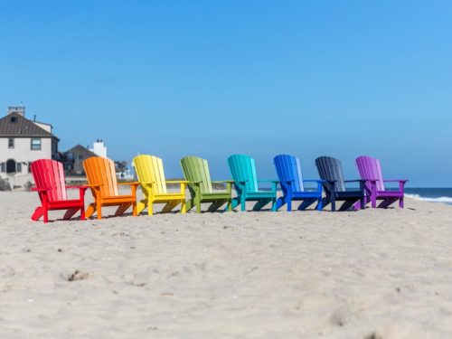 multicolored outdoor furniture sitting on beach in front of shore homes