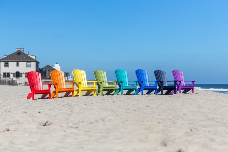 multicolored outdoor furniture sitting on beach in front of shore homes