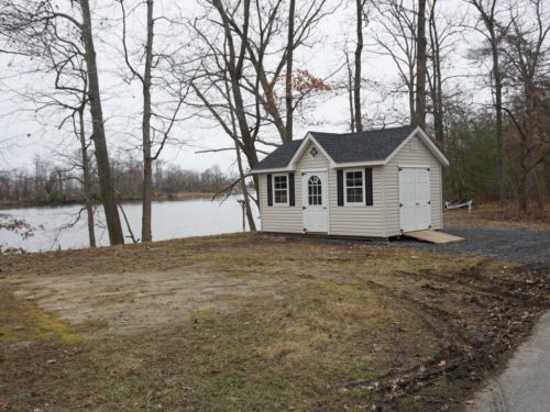 classic a frame dormer shed sitting next to trees and lake