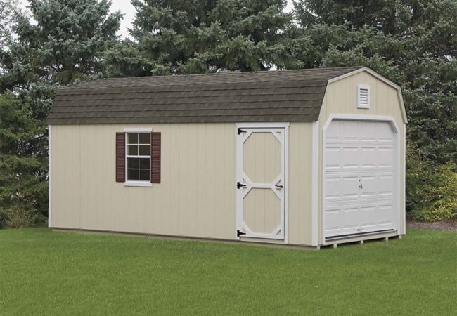 tan dutch barn garage with white door and asphalt shingles sitting green grass