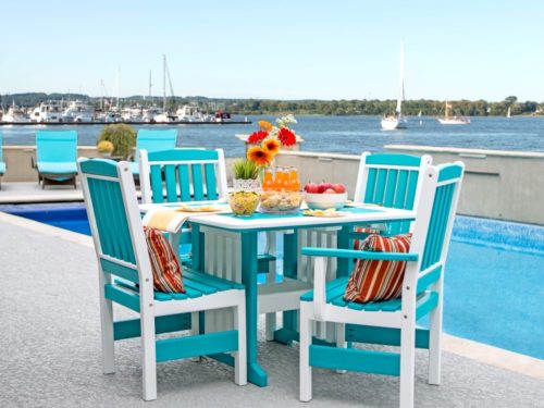 teal and white lawn furniture sitting next to pool overlooking the bay