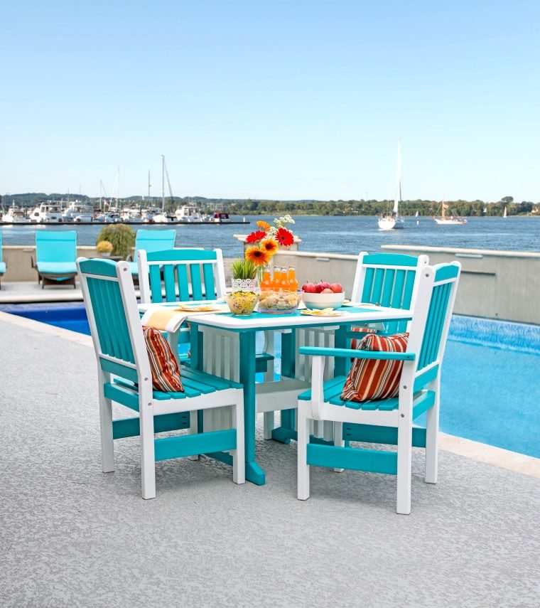 teal and white lawn furniture sitting next to pool overlooking the bay