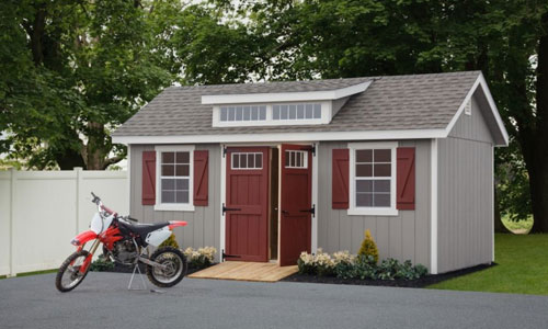 backyard man cave shed with red dirt bike parked out front